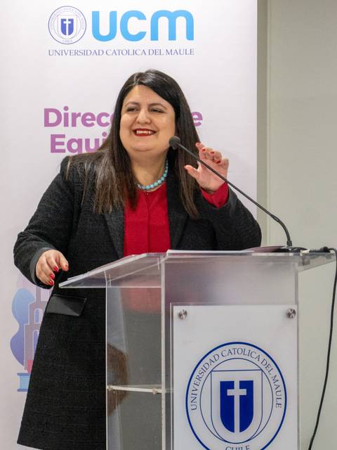 Una profesional se encuentra en el podio durante un evento en la Universidad Católica del Maule.