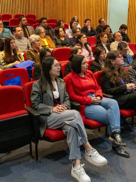 Un grupo de personas sentadas en un auditorio durante una charla.