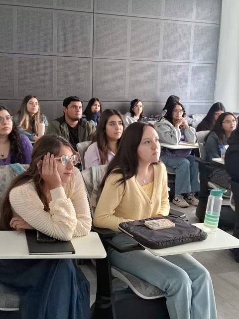 Un grupo de estudiantes atentos en una sala de clases escuchando una lección.