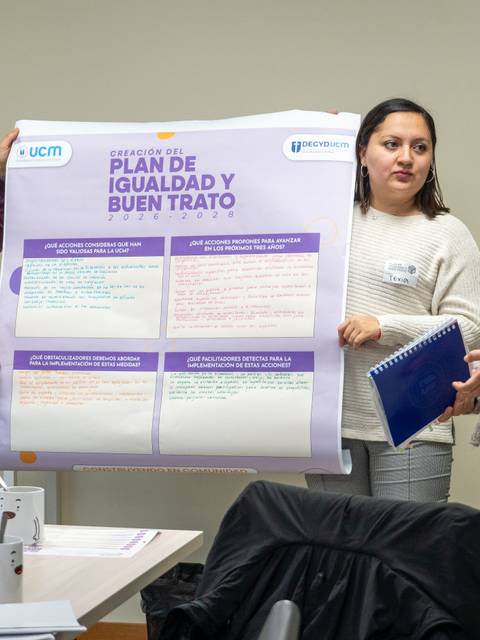 Un grupo de tres personas presenta un cartel sobre un plan de igualdad y buen trato en una reunión.