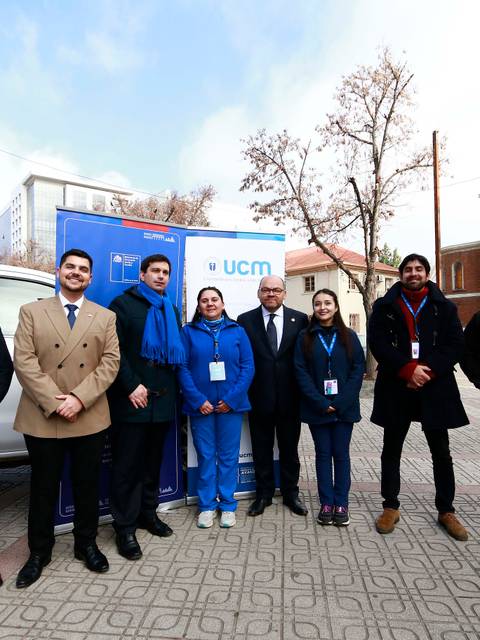 Un grupo de personas vestidas de manera formal y profesional, posando junto a un vehículo en un ambiente urbano.