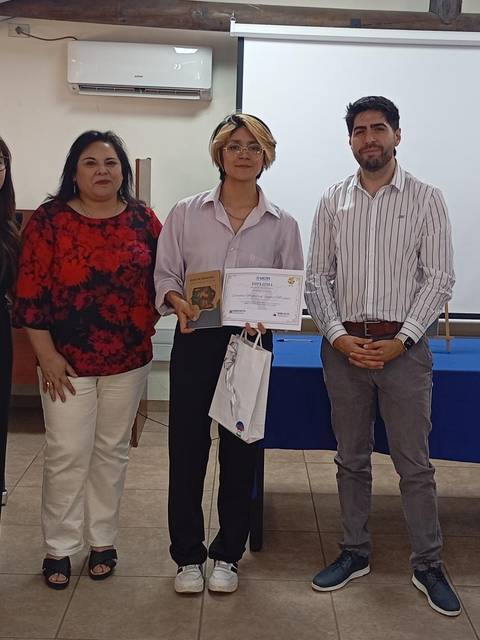 Un grupo de personas posando con un certificado en un evento de la UCM.