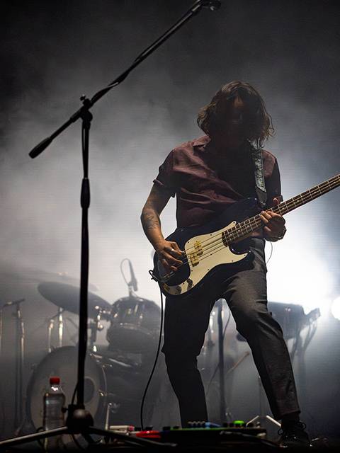 Un músico tocando el bajo en un ambiente de concierto con luces dramáticas.