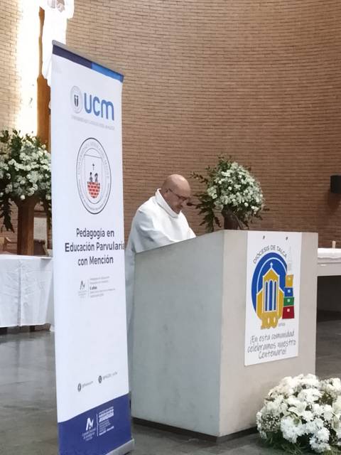 Un sacerdote oficia una ceremonia en un espacio con decoración floral.