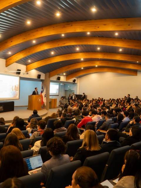 Una gran audiencia en un auditorio, escuchando a un expositor en una charla.