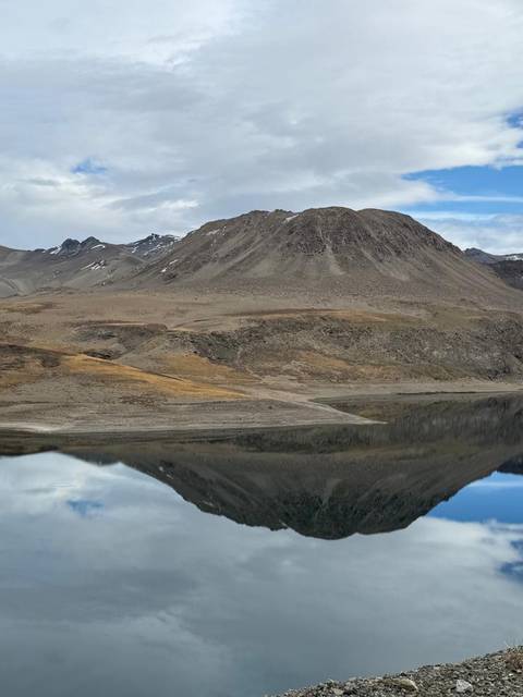 Un paisaje montañés con un lago que refleja el cielo.