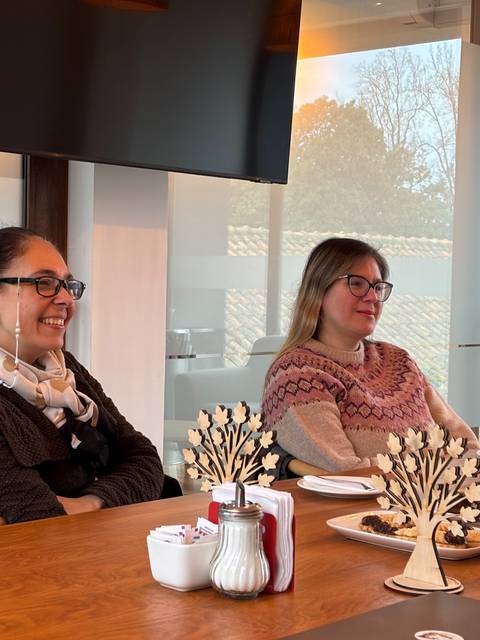 Dos mujeres conversan y disfrutan de un rico coffee break en una reunión.