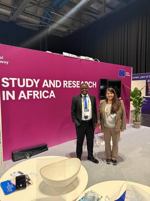Dos personas posan junto a un stand con el lema 'Study and Research in Africa'.