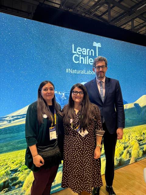 Tres personas posando frente a un fondo que promociona Chile como un lugar natural de oportunidades.