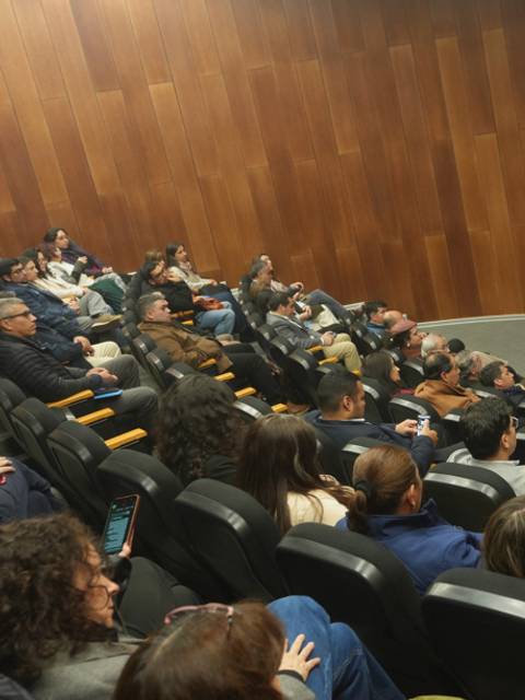Una charla en una sala llena donde un expositor presenta a los asistentes.