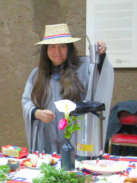En una mesa decorada con motivos chilenos, dos mujeres preparan alimentos típicos para una celebración.