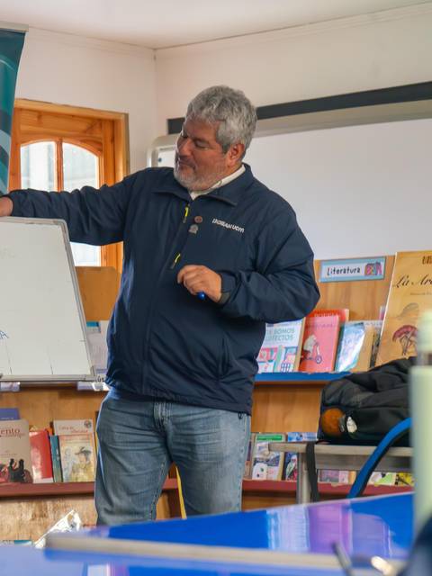 Dos hombres están presentando ideas en una pizarra durante una reunión en un espacio comunitario.
