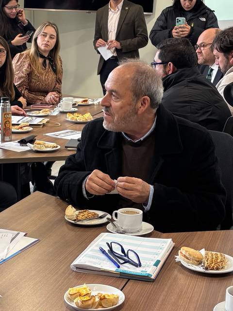 Un grupo de personas conversando y compartiendo un desayuno en una reunión amistosa.