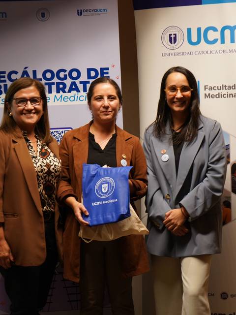 Tres mujeres posando sonrientes en un evento relacionado con la medicina en la Universidad Católica del Maule.
