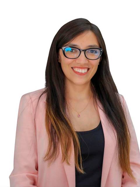 Una mujer sonriente con lentes y chaqueta rosa.