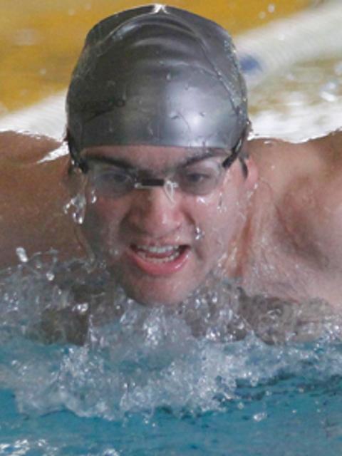 Un nadador compitiendo en la piscina con gran esfuerzo.