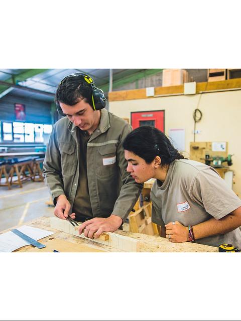 Un par de estudiantes en un taller de carpintería trabajando juntos en un proyecto.