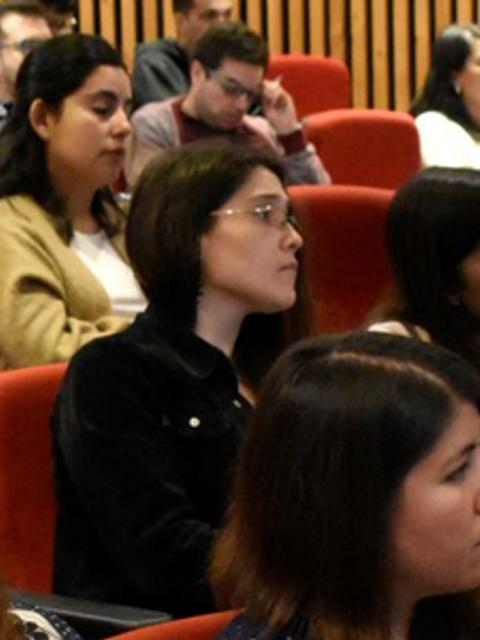 Un grupo de personas escuchando atentamente en una charla o presentación en un auditorio.