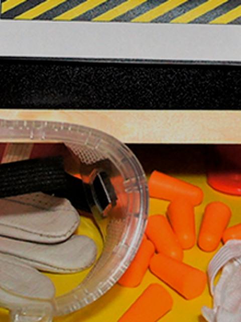 La imagen muestra equipos de seguridad, incluyendo gafas y mascarillas, sobre una superficie amarilla.