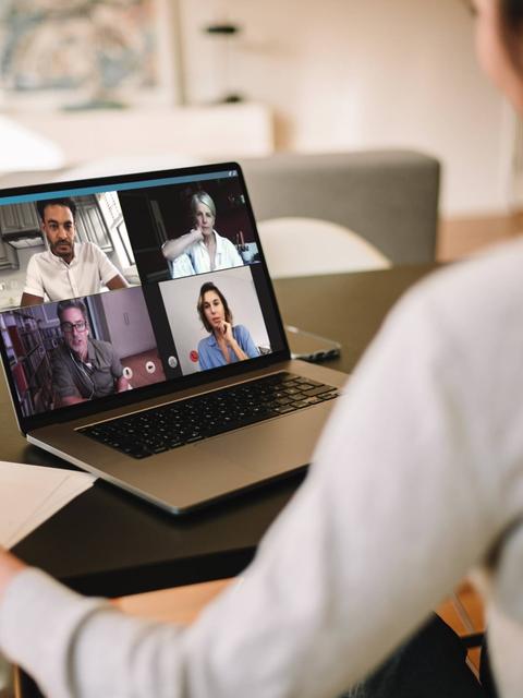 Una persona participa en una videollamada con varias personas en una pantalla.