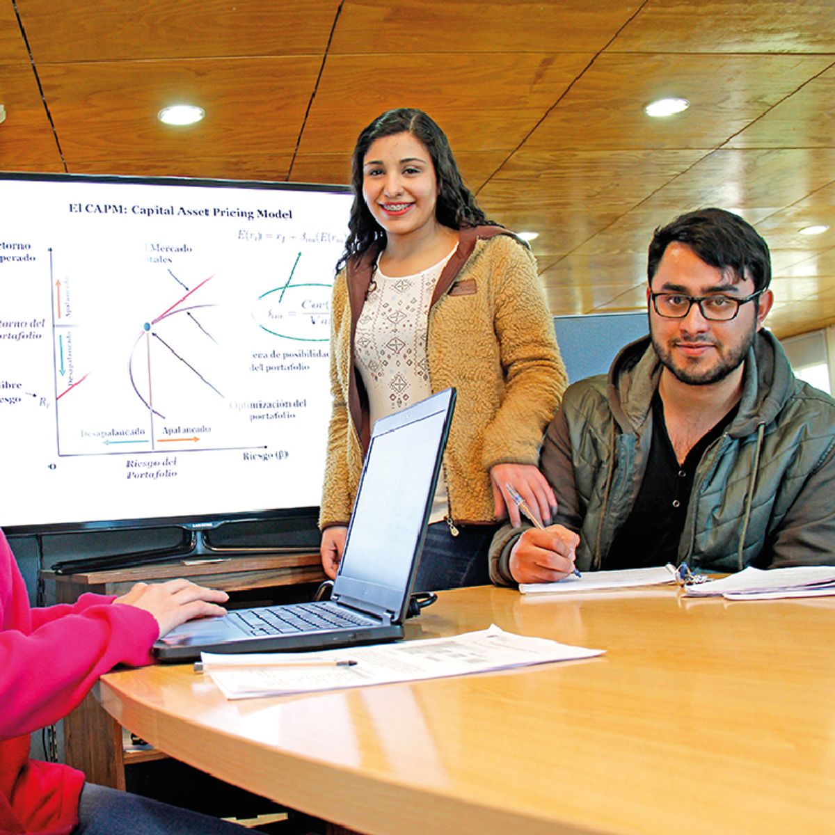 Un grupo de estudiantes discutiendo un modelo financiero frente a una computadora.