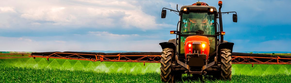 Un tractor agrícola trabajando en un campo verde bajo un cielo nublado.