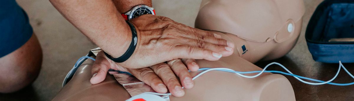 Una persona está realizando maniobras de reanimación cardiopulmonar sobre un maniquí.