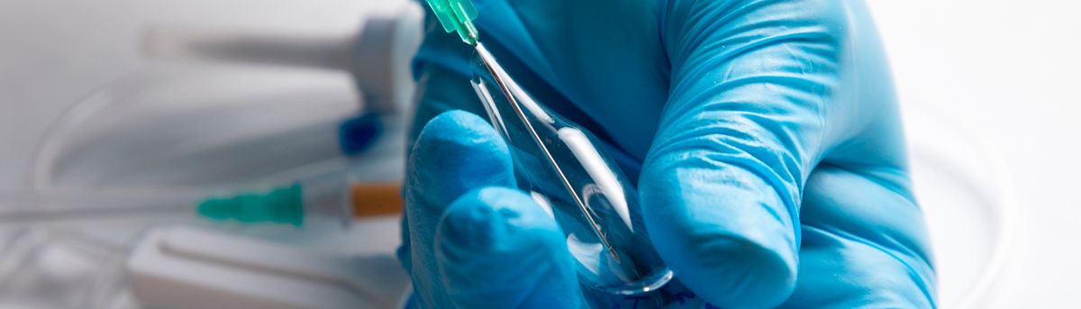 Una mano con guante azul sostiene un instrumento médico.