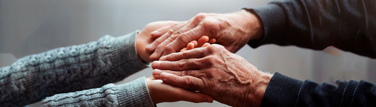 Las manos de una persona mayor y una menor se entrelazan en un gesto de unión y cariño.