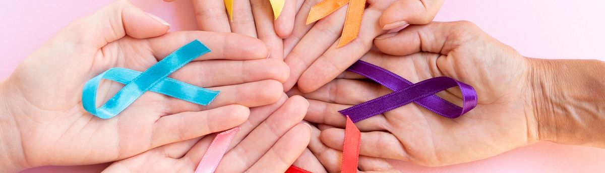 Varias manos sostienen cintas de diferentes colores sobre un fondo rosa.