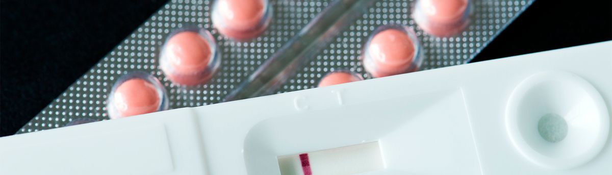 La imagen muestra un test de embarazo junto a un blíster de pastillas.