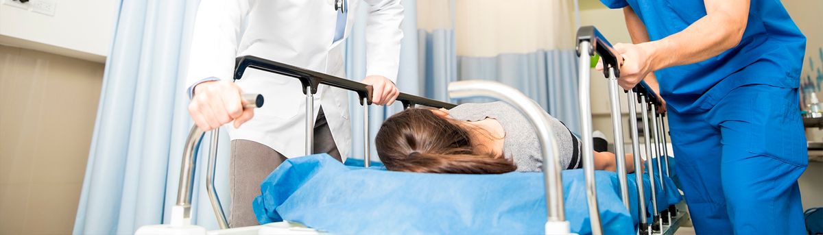 Un médico y un enfermero trasladan a una paciente en una camilla dentro de un hospital.