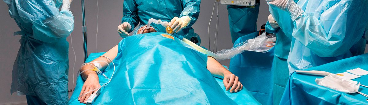 Un equipo médico asiste a un paciente durante una cirugía en un entorno estéril.
