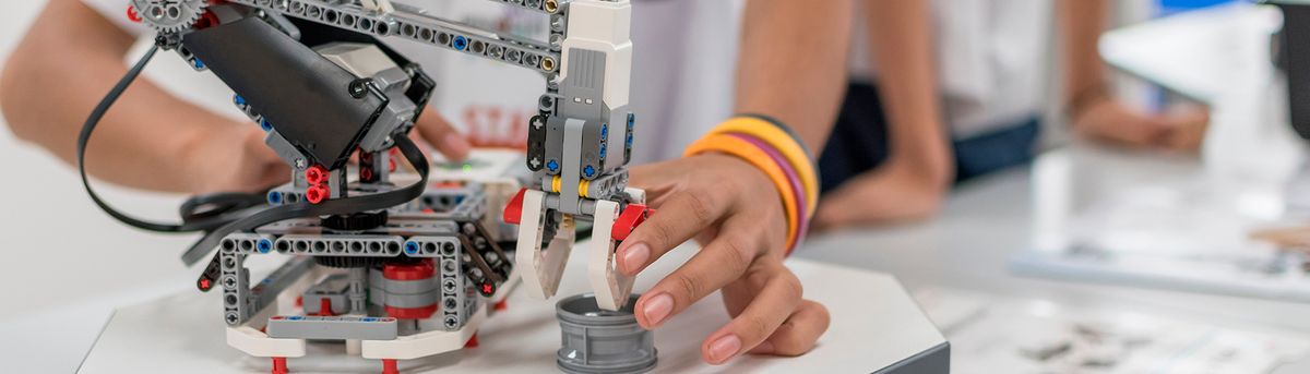 Un robot mecánico está siendo manipulado por una persona que sostiene una pieza en la mano.