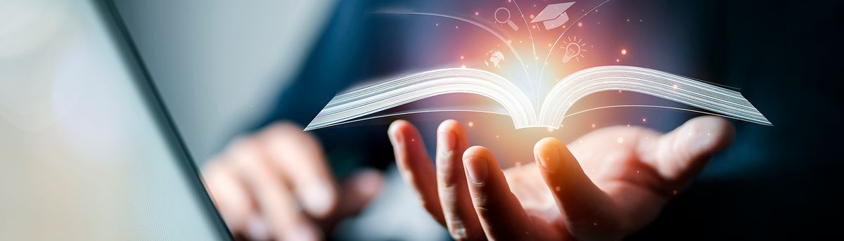 Una mano sostiene un libro abierto con destellos de luz que emanan de sus páginas.