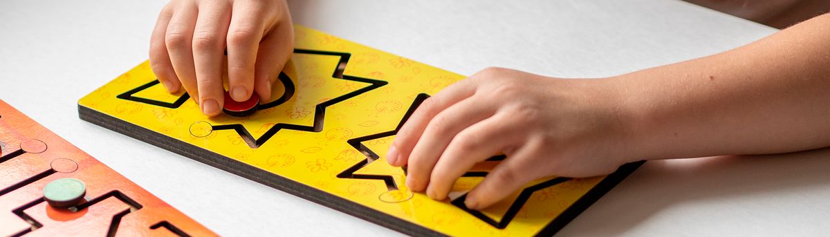 Un niño está jugando con un rompecabezas de formas de colores en una mesa.