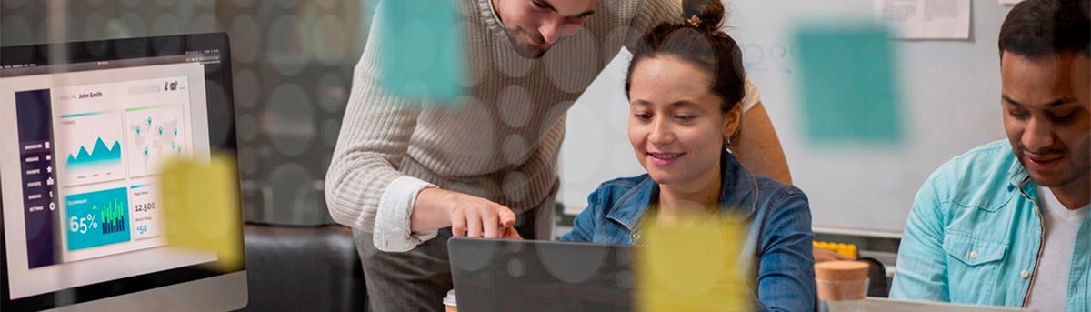 Un grupo de personas colaborando en un entorno de oficina mientras trabajan en un ordenador portátil y analizan gráficos en una pantalla.