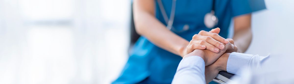 Un profesional de la salud sostiene las manos de un paciente en un gesto de apoyo y cuidado.