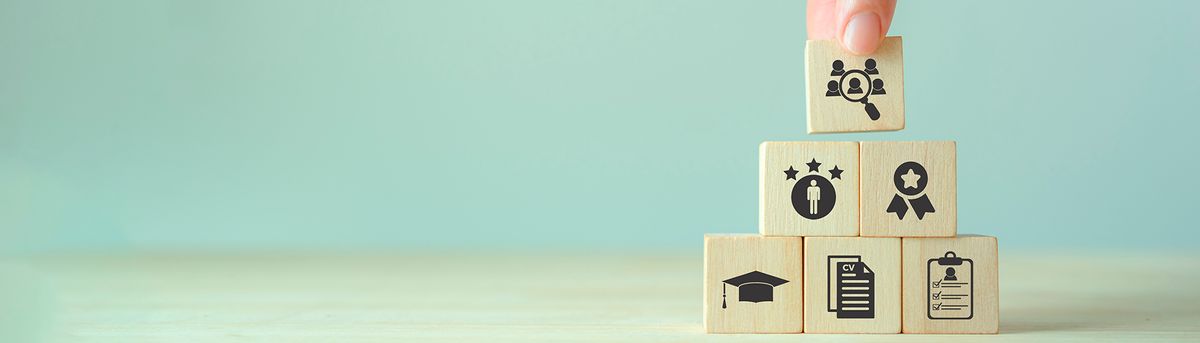 Un hombre está colocando un bloque en una torre de bloques de madera con iconos sobre la educación y logros.