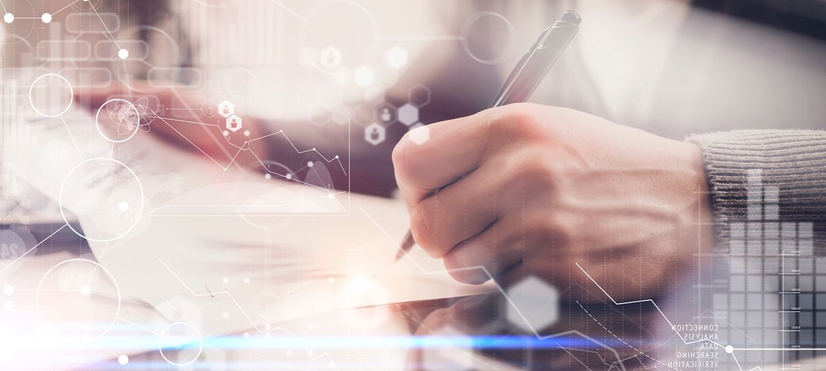 Una persona escribiendo en una hoja con un fondo de gráficos digitales.