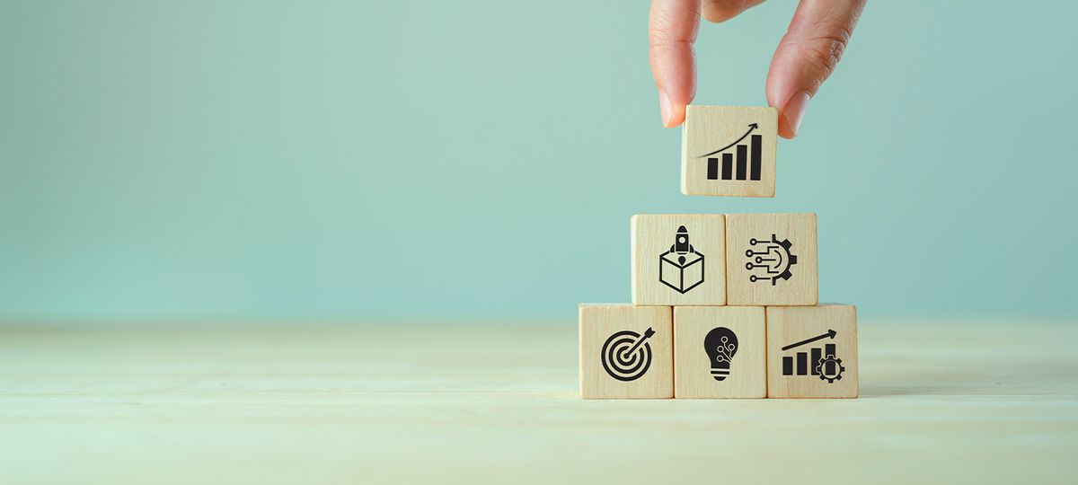 Una mano coloca un bloque con un gráfico sobre una torre de bloques de madera que representan ideas de crecimiento y desarrollo.