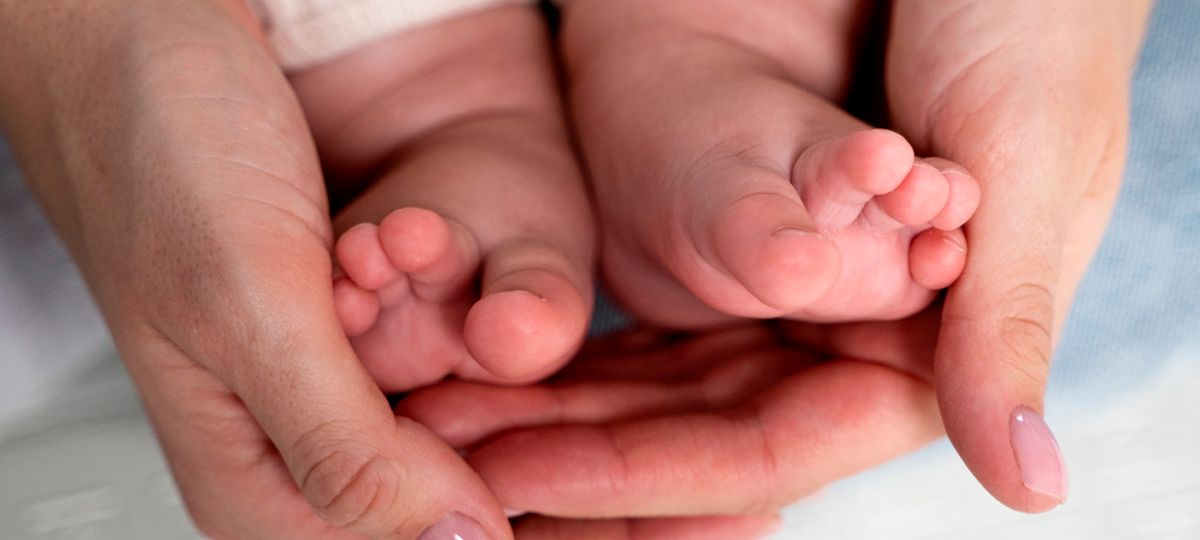 Unas manos sosteniendo los pies de un bebé.