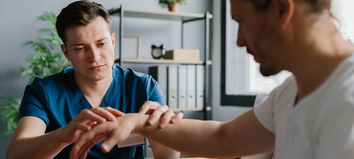 Un profesional de la salud está evaluando la mano de un paciente.