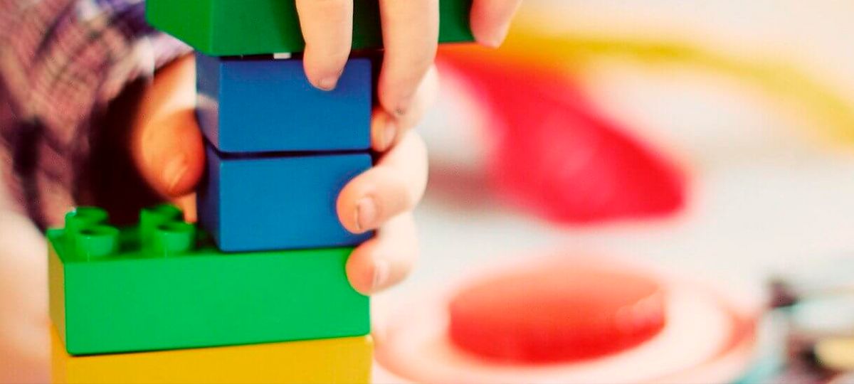 Un niño apila bloques de colores brillantes sobre una mesa.