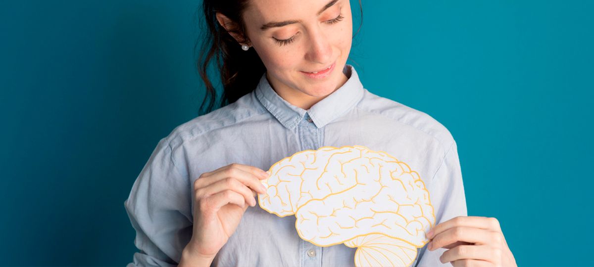 Una mujer con una blusa azul sostiene un modelo de cerebro de papel.