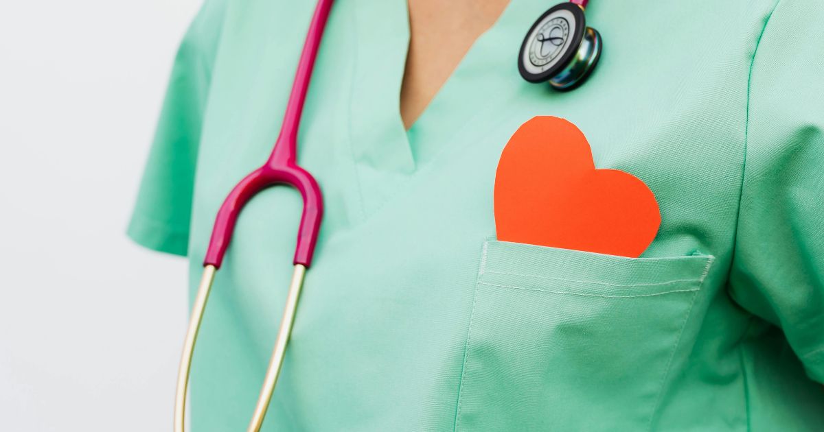 Un doctor con una bata verde y un corazón de papel en su bolsillo.