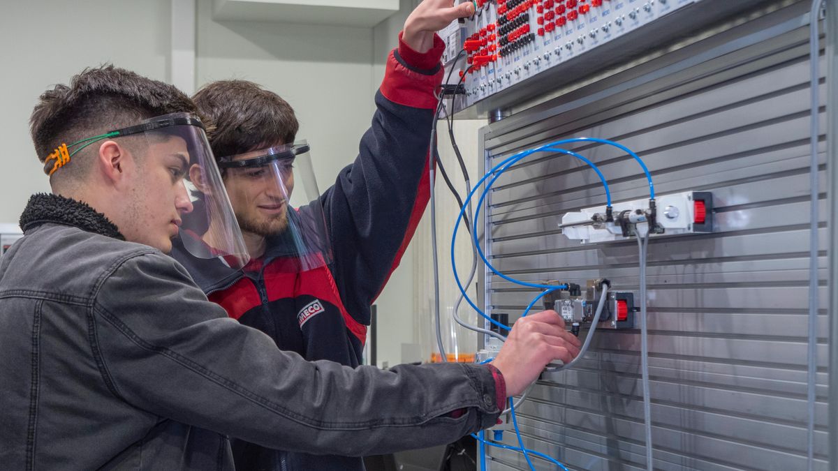 Dos personas en un entorno educativo trabajan juntas en un ejercicio práctico de electricidad.