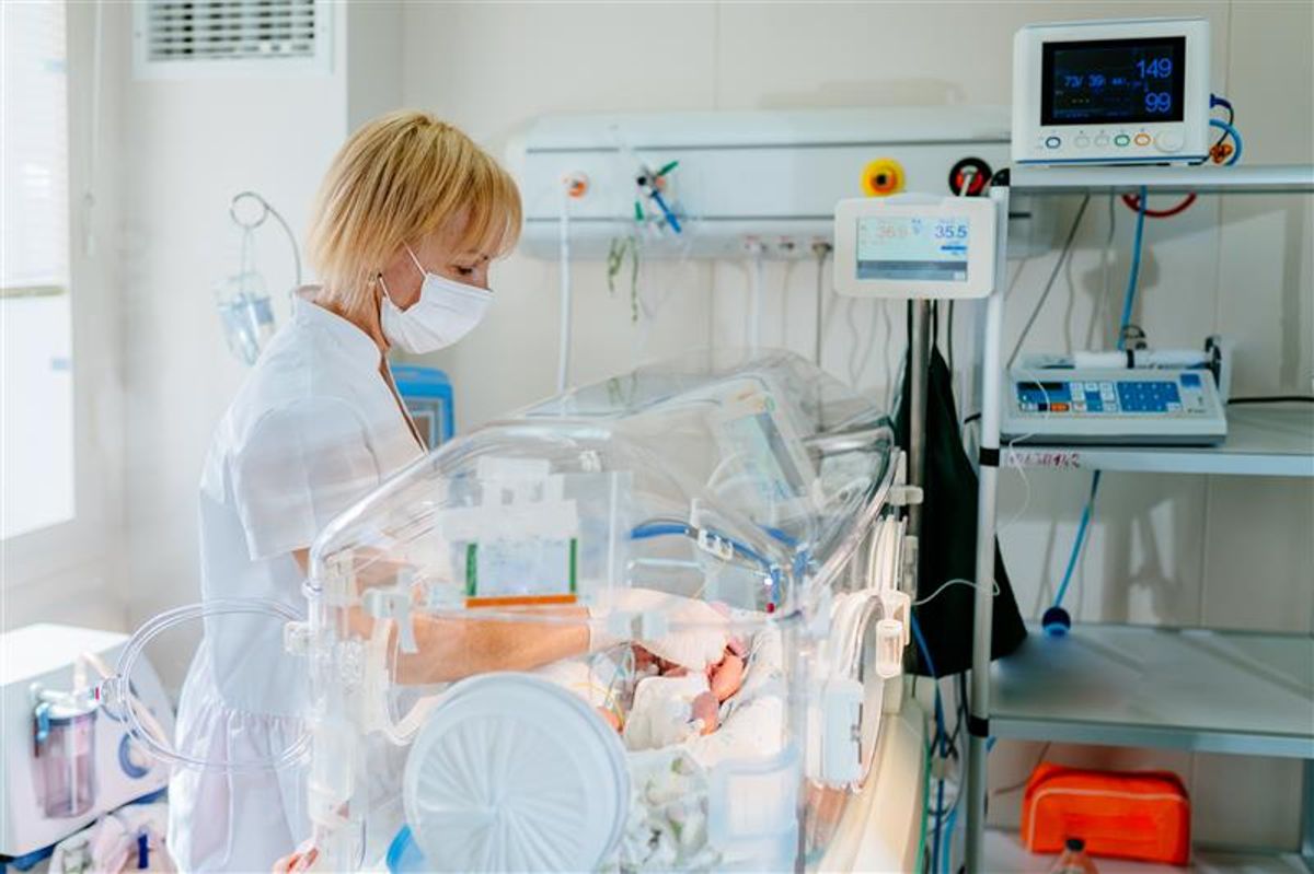 Una enfermera cuida a un recién nacido en una incubadora en un hospital.