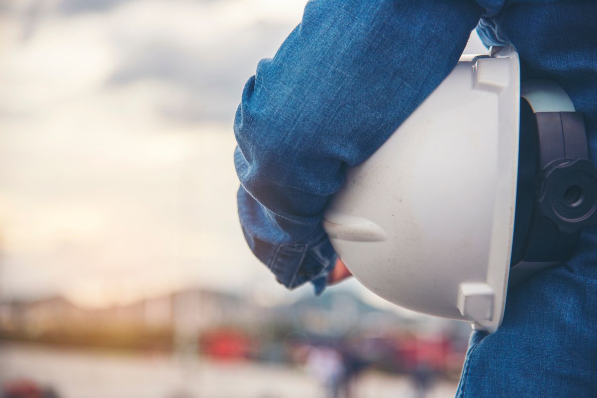 Un trabajador sosteniendo un casco de seguridad en un entorno laboral.