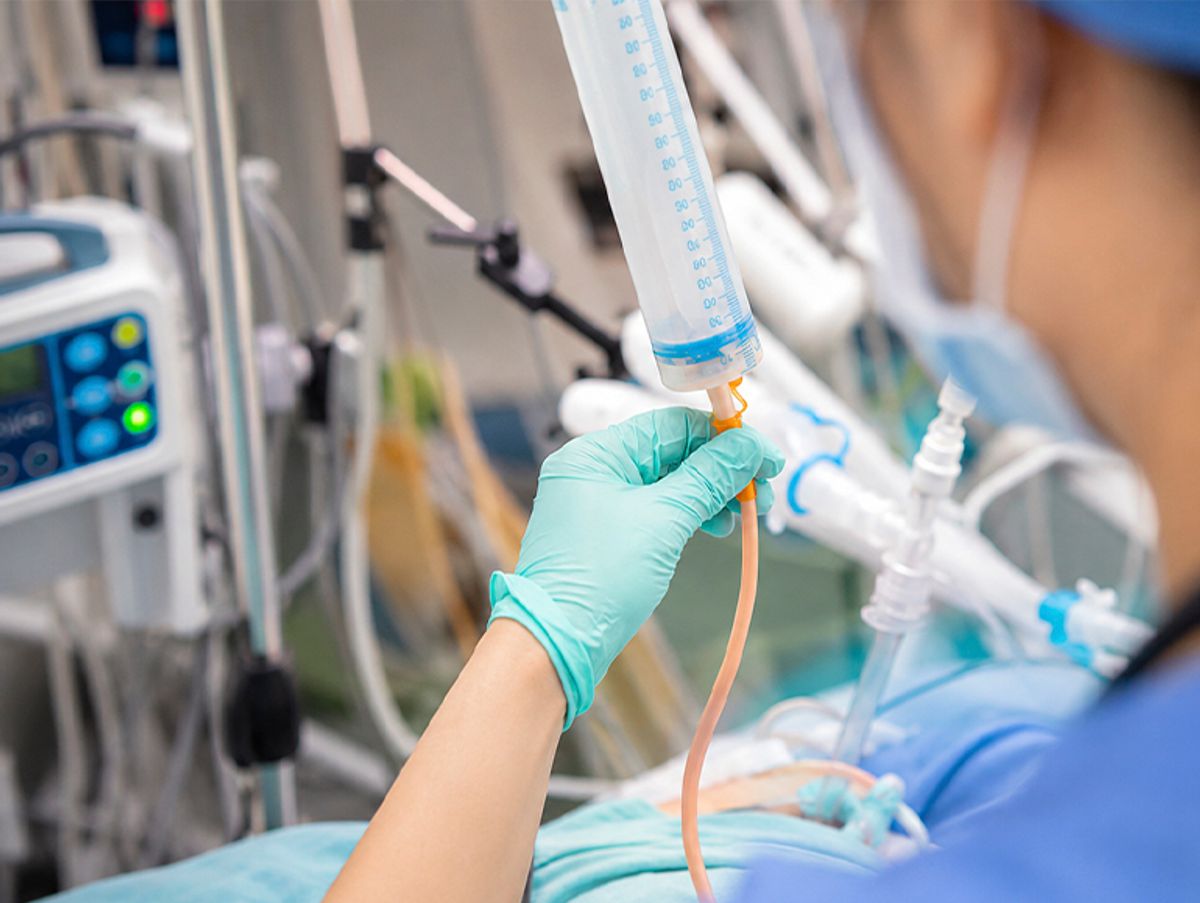 Una persona en un entorno hospitalario manipula un frasco de medicamento mientras está equipada con guantes.